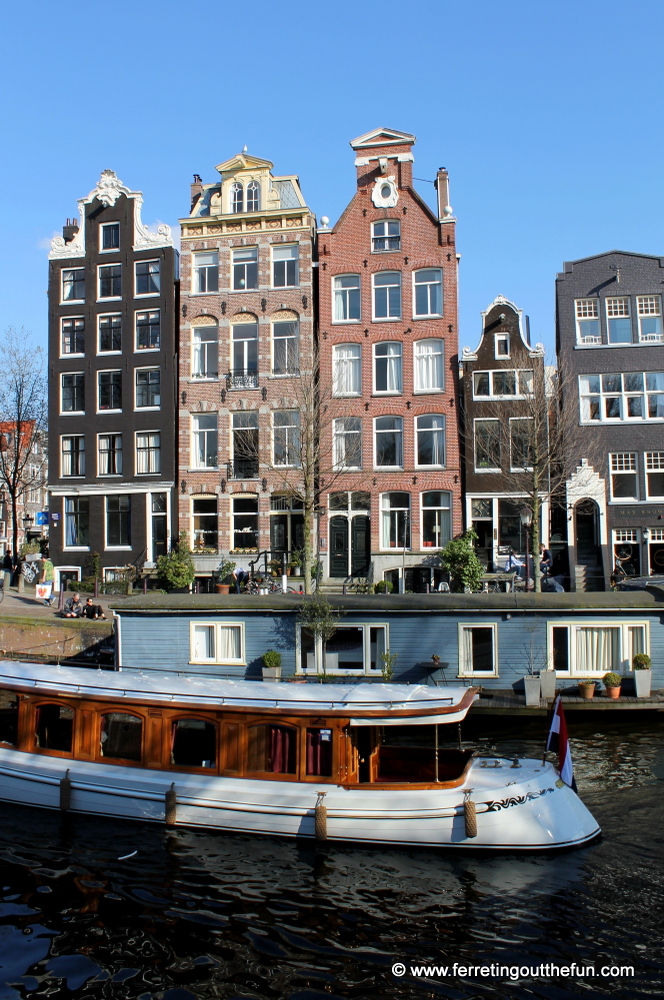 A canal boat cruises past unique Dutch houses in Amsterdam, Netherlands