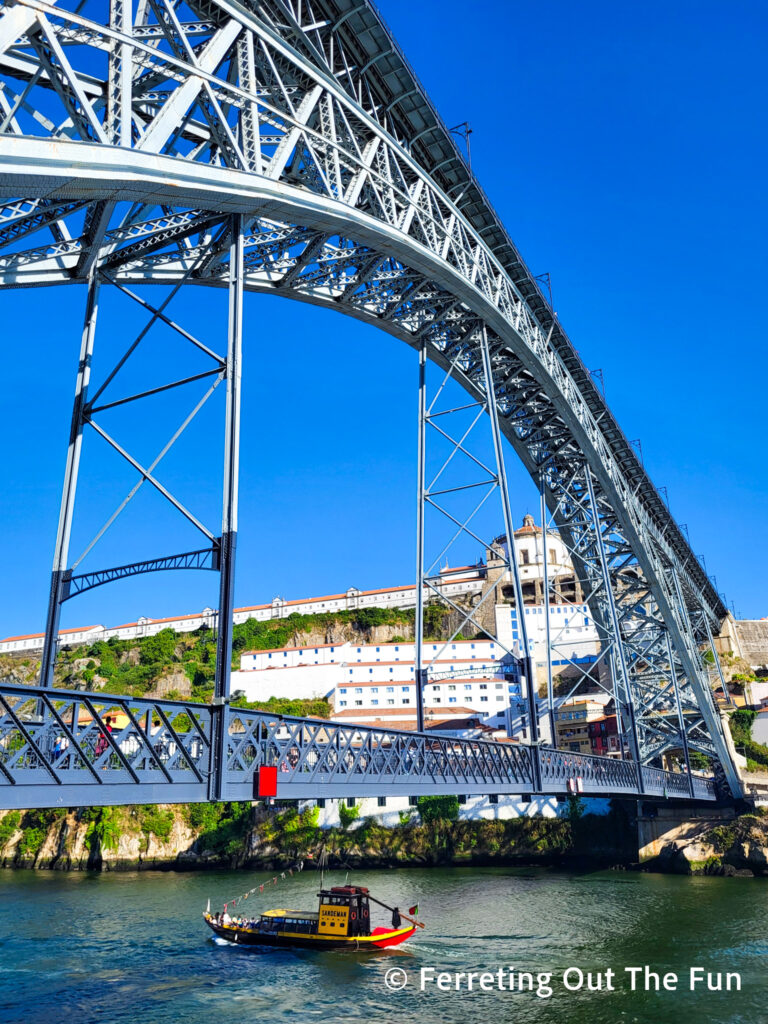 A small boat crosses under the Luis I Bridge in Porto