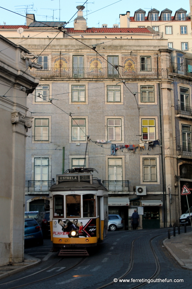 A yellow tram and tile facade in the Alfama district of Lisbon, Portugal.