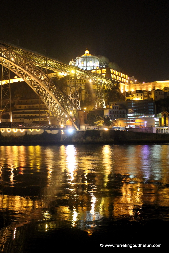 The golden lights of Luis I Bridge reflect on the Douro River // Porto, Portugal