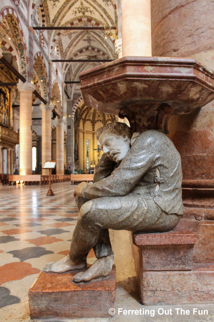 A hunchback sculpture holds up the holy water stoup in the Basilica di Sant'Anastasia in Verona, Italy