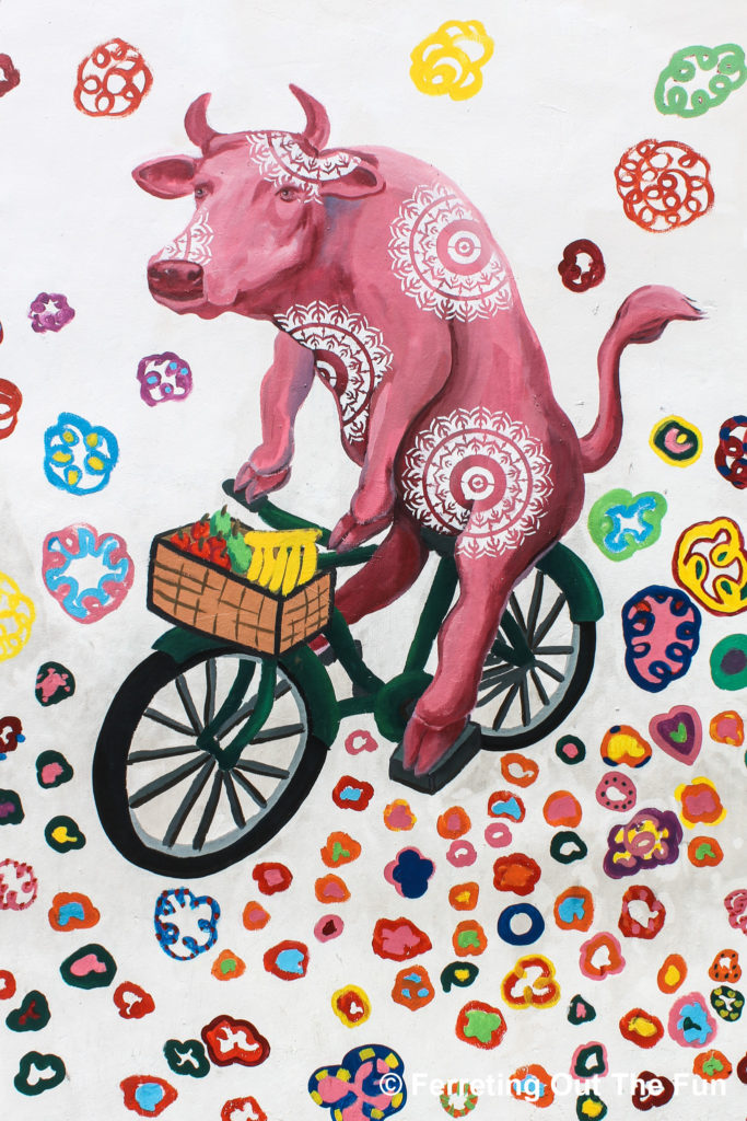 Street art mural of a cow riding a bike in Singapore's Little India