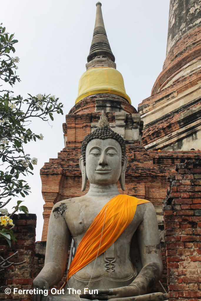 A large Buddha statue sits next to Ayutthaya temple ruins in Thailand