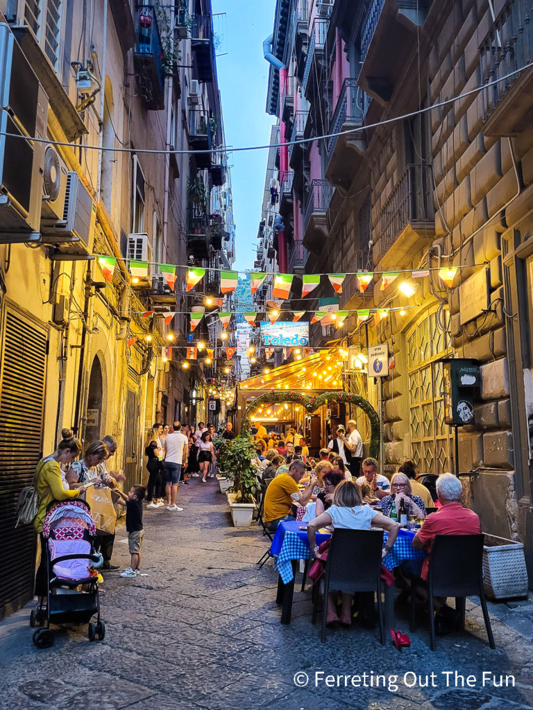 Al fresco dining in a colorful alleyway in Naples, Italy