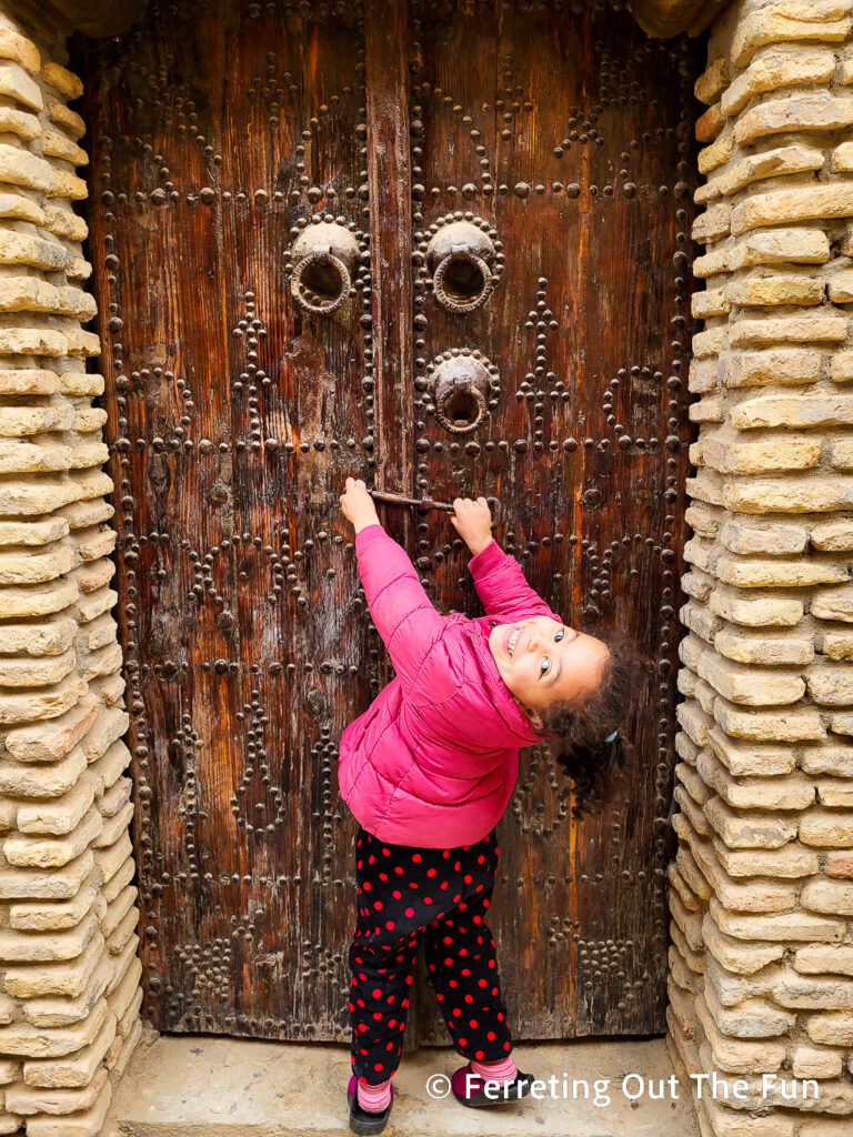 A little girl poses in front of an old door in Tozeur Tunisia